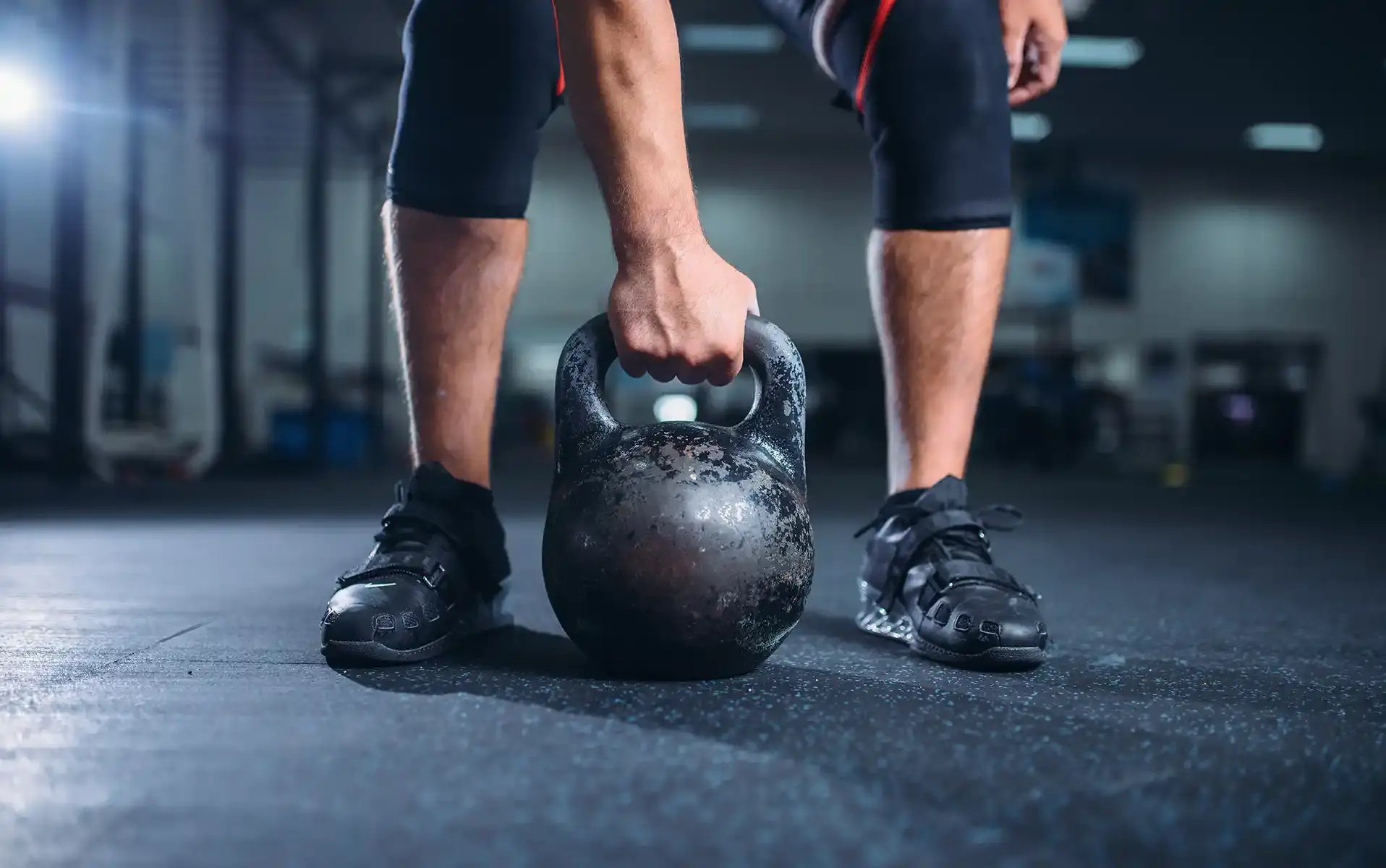 man working out in a gym about to lift a kettle bell